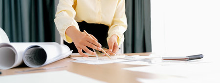 Professional architect team used divider measure during draft blueprint on table with architectural...