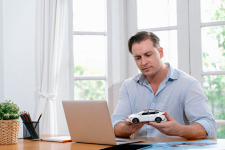 Car design engineer analyze car model prototype for automotive business company at home office. Vehicle designer holding scale car, carefully analyzing looking for any flaw or improvement. Synchronosの写真素材