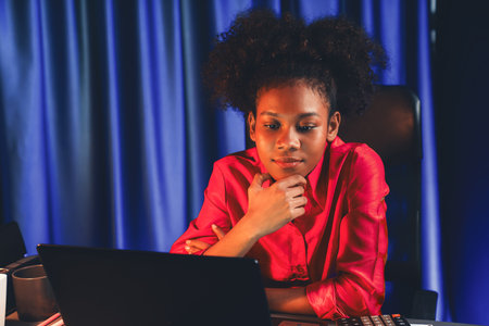 African woman blogger wearing pink shirt with happy face, looking on screen laptop with valued achievement project or get scholarship. Concept of cheerful expression work from home. Tastemaker.の写真素材