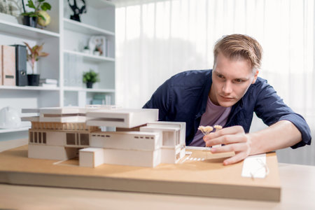 Architect designer studies elegant house model, reviewing structure design for improvement with construction plan on table. Creativity and innovation in architectural design. Iterationの写真素材