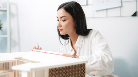 Closeup portrait image of professional young beautiful engineer architect using triangular scale measures house model with focusing at modern office. Business creative design concept. Immaculate.の写真素材
