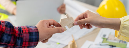 Professional engineer and architect collaborate on eco house project at meeting table with green design blueprint and architectural equipment at modern office. Focus on hand. Close up. Delineation.の写真素材