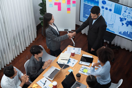 Diverse coworker celebrate with handshake and teamwork in corporate workplace. Happy business people united by handshaking after successful meeting or business presentation on data analysis. Concordの写真素材