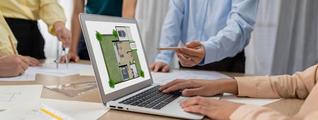 Professional architect decide the blueprint for eco-friendly house during discussion about changing blueprint plan at meeting table with architectural document scatter around. Closeup. Delineationの写真素材