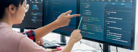 Female programer explain while pointing code displayed on computer. Professional programmer present...