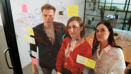 Young creative start up business team brainstorming idea and solving problems by using colorful sticky note and mind map at glass board, modern meeting room. discussing, working together. Immaculate.の写真素材