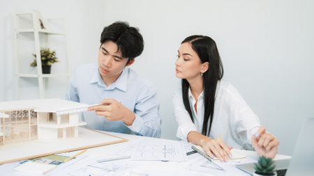 Professional male engineer measure house model by using ruler while beautiful cooperative coworker...