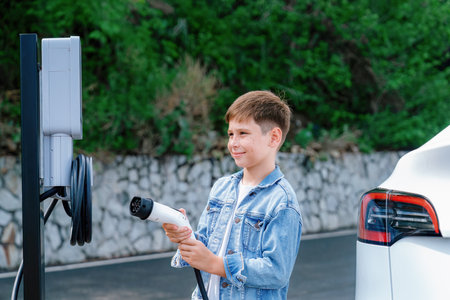 Little boy recharging eco-friendly electric car from EV charging station. EV car road trip travel concept for alternative transportation powered by clean renewable and sustainable energy. Perpetualの写真素材