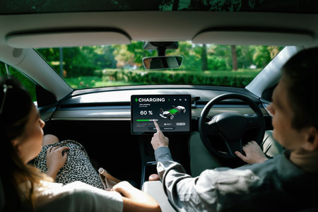 Electric car driver checks battery charging status, range and charging limit on app screen in the car. Smart technology device show EV car recharging data of electric storage in car battery innards.の写真素材
