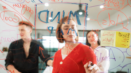 Creative business team brainstorming and sharing marketing idea about start up project by writing down on colorful sticky note at glass board modern meeting room. Working together. Immaculate.の写真素材