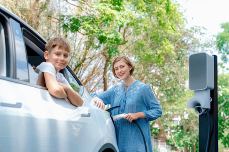 Family road trip vacation with electric vehicle, mother and son recharge EV car with green and clean energy. Nature and travel with eco-friendly car for sustainable environment. Perpetualの写真素材