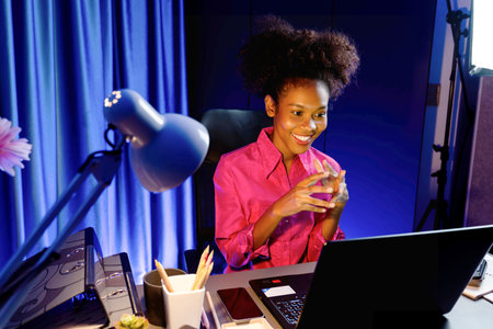 Working African woman with happy glowing, smiling face, getting new job project with good deal or marketing course scholarship information on laptop screen. Concept of cheerful expression. Tastemaker.の写真素材