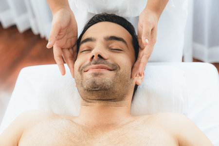 Caucasian man enjoying relaxing anti-stress head massage and pampering facial beauty skin recreation leisure in dayspa modern light ambient at luxury resort or hotel spa salon. Quiescentの写真素材