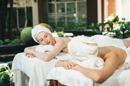 A portrait of a couple of a beautiful young caucasian woman with white towel rest on comfortable spa bed with relaxation while having body massage with professional masseur at spa salon.Tranquility.の写真素材