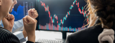 Happy successful business people celebrate while look at increasing stock market chart on black background displayed on computer. Smart investor cheering their success investment. Burgeoning.の写真素材