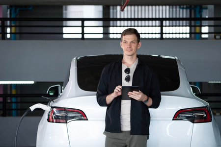 Young man travel with EV electric car to shopping center parking lot charging in downtown city...