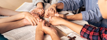 Cropped image of diversity people hand praying together at wooden church on bible book while hold hand together with believe. Concept of hope, religion, faith, god blessing concept. Burgeoning.の写真素材