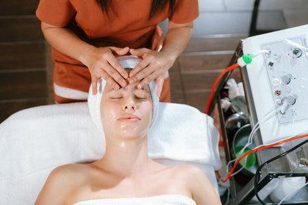 Beautiful young women with beautiful skin having facial massage surrounded by professional therapist using beauty electrical equipment. Top view. Healthy and beauty concept. Tranquility.の写真素材