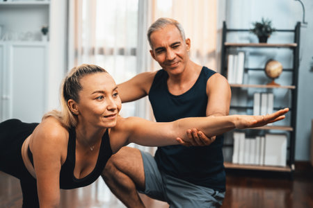 Happy active senior couple in sportswear being supportive and assist on yoga posture together at...