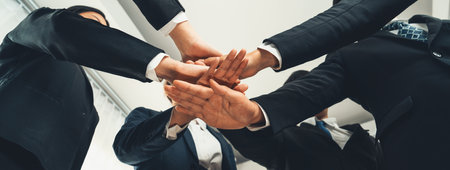 Office worker team stacking hand together symbolize successful group of business partnership and strong collective unity teamwork in community workplace in panoramic banner. Shrewdの写真素材