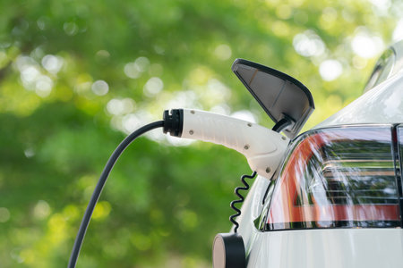Closeup EV electric car recharge battery at parking lot in green city park. Alternative clean energy technology for rechargeable automobile for sustainable and eco friendly urban travel. Expedientの写真素材
