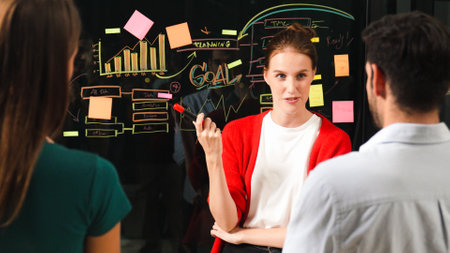 Closeup of young beautiful project manager present graph and business plan on glass wall. Skilled...