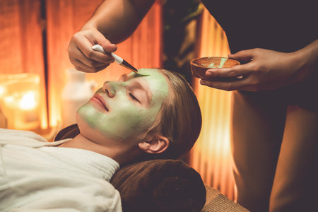 Serene ambiance of spa salon, woman customer indulges in rejuvenating with luxurious face cream massage with warm lighting candle. Facial skin treatment and beauty care concept. Quiescentの写真素材