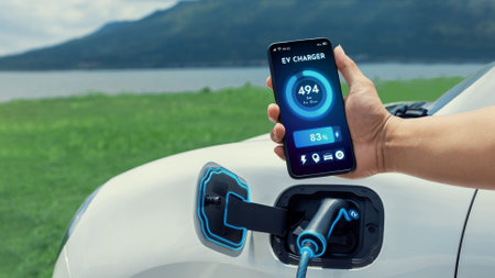 Businessman holding smartphone display battery status interface by smart EV mobile application while...