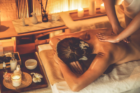 Caucasian woman customer enjoying relaxing anti-stress spa massage and pampering with beauty skin recreation leisure in warm candle lighting ambient salon spa at luxury resort or hotel. Quiescentの写真素材