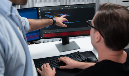 IT developers pointing on software development information on two screens with coding program in...