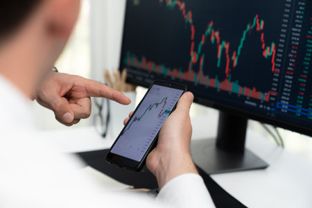 Investor stock trading with serious face sharing with coworker while drinking coffee by using...