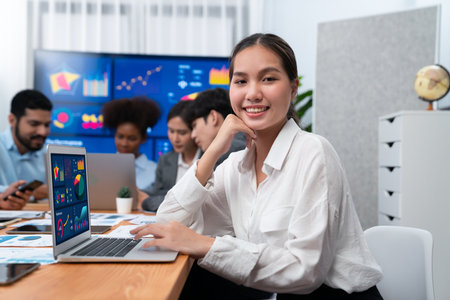 Portrait of happy young asian businesswoman with group of office worker on meeting with screen display business dashboard in background. Confident office lady at team meeting. Concordの写真素材