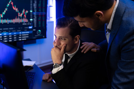 Stressful two stock investors with disappointed face focusing on dynamic currency market graph in...