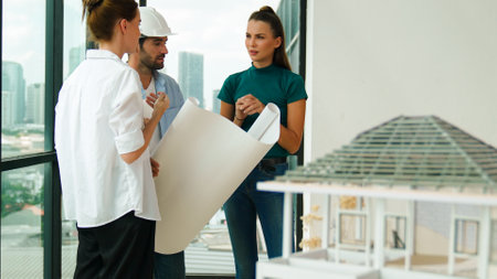 Professional architect engineer team talking, sharing, brainstorming about design while manager hold at project plan. Young architect holding plan while manager listen and point at plan. Traceryの写真素材