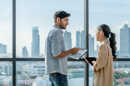 Professional businessman present financial statistic to investor while standing near panoramic window shows skyscraper or city view. Diverse businesspeople discuss about marketing plan. Tracery.の写真素材