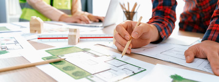 A cropped portrait of professional architect working with blueprint during safety engineer using...