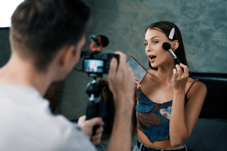 Man filming video on young woman making beauty and cosmetic tutorial video content for social media. Beauty blogger smiles to camera while showing how to beauty care to audience or follower. Unveilingの写真素材
