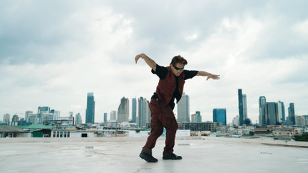 Motion shot of B-boy dance performance by professional street dancer at rooftop with sky scrapper, city view. Attractive asian hipster show energetic footstep. Outdoor sport 2024. Endeavor.の写真素材