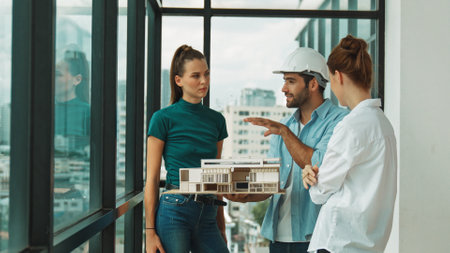 Skilled engineer holds house model and explain about house construction to skilled manager. Group of...