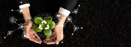 Businessman nurturing and growing plant seedling with recycle symbol. Business commitment and investing in natural and environmental protection future sustainable ecosystem. Panorama Relianceの写真素材