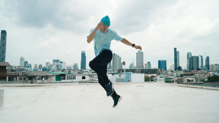Caucasian B-boy dancer practicing street dancing at rooftop with city urban view. Motion shot of young man performing street dance by moving with hip -hop music. Outdoor sport 2024. Endeavor.の写真素材