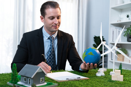 Eco business and save Earth concept shown by businessman or CEO holding paper globe in office with...