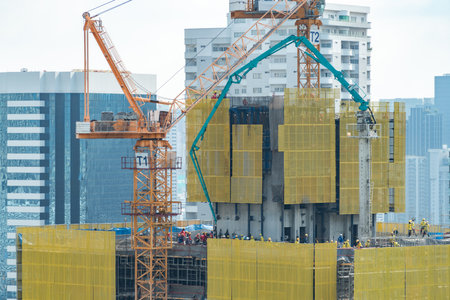 Image of exterior skyscrapers construction site with tower cranes. Cityscape under construction with cranes working moving to renovate building. Blue sky background. Architectural. Ornamented.の写真素材