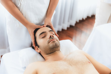 Caucasian man enjoying relaxing anti-stress head massage and pampering facial beauty skin recreation leisure in dayspa modern light ambient at luxury resort or hotel spa salon. Quiescentの写真素材