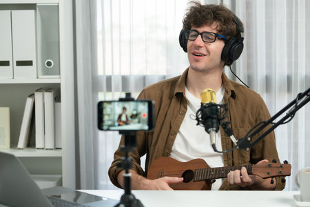 Host channel of influencer singing with playing guitar in broadcast modern home studio to fanclub. Time slot of music blogger showing on live social media online on cellphone in audio creator. Gusher.の写真素材