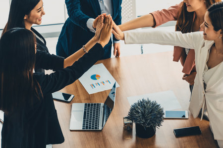 Businesswomen joining hands in group meeting at modern office room showing teamwork, support and...