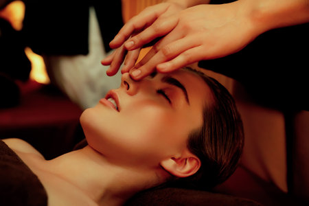 Caucasian woman enjoying relaxing anti-stress head massage and pampering facial beauty skin recreation leisure in warm candle lighting ambient salon spa in luxury resort or hotel. Quiescentの写真素材