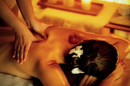 Caucasian woman customer enjoying relaxing anti-stress spa massage and pampering with beauty skin recreation leisure in warm candle lighting ambient salon spa at luxury resort or hotel. Quiescentの写真素材