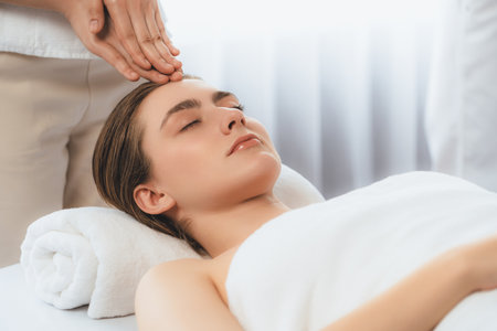 Caucasian woman enjoying relaxing anti-stress head massage and pampering facial beauty skin recreation leisure in dayspa modern light ambient at luxury resort or hotel spa salon. Quiescentの写真素材