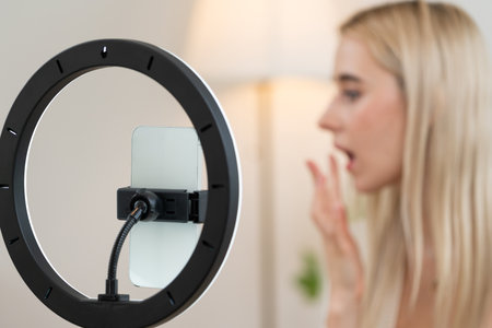 Blurred young woman making beauty and cosmetic tutorial video content for social media. Focused camera while beauty influencer showing how to apply beauty care to audience or followers. Blitheの写真素材
